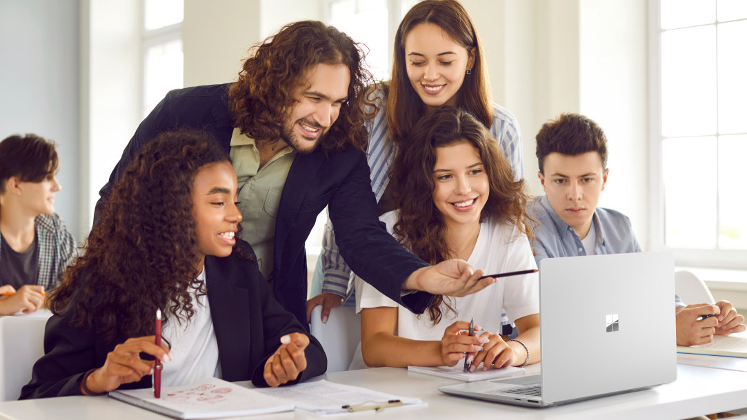 A teacher and students looking at a Surface laptop