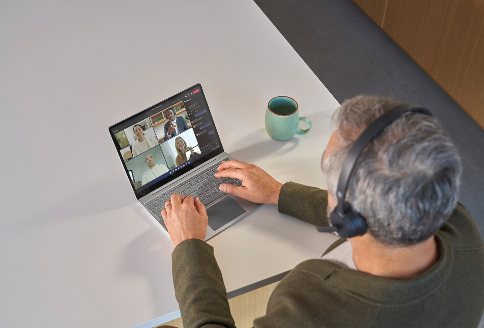 En person, der bærer Surface Headphones 2 i et Teams-møde på sin Surface Laptop Go 2, set oppefra
