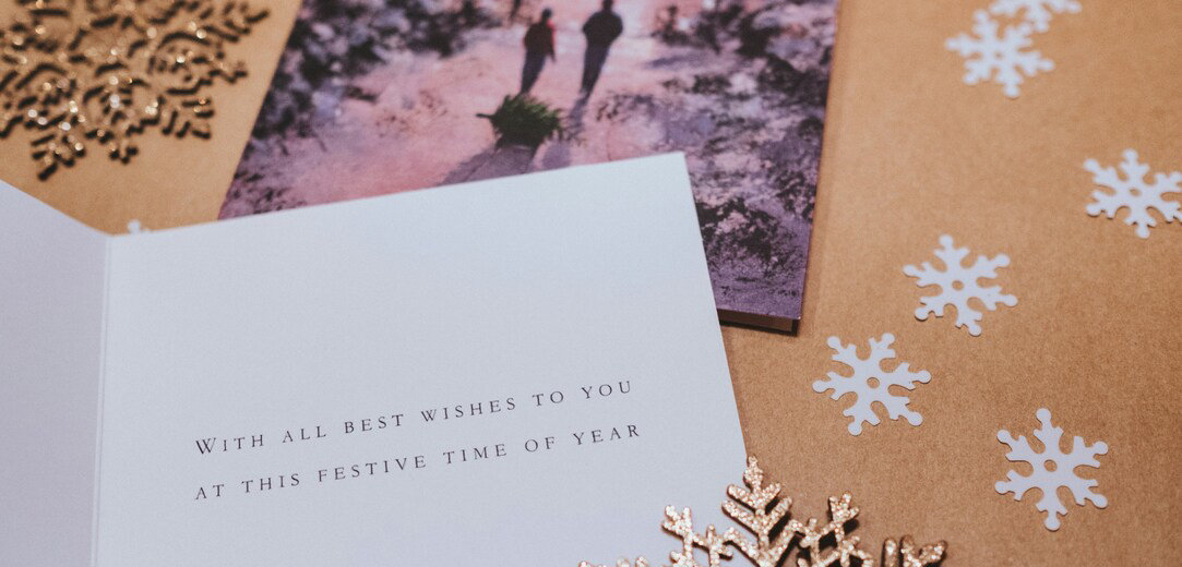 A white greeting card on a brown background and cut out paper snowflakes