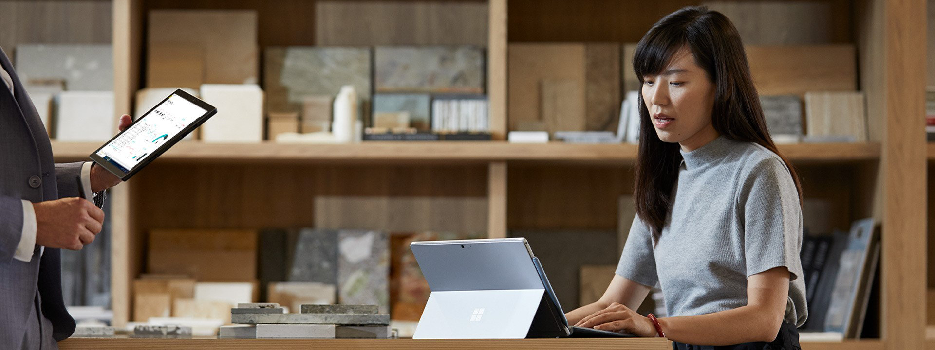 一位女性和她的同事一边使用 Surface 设备，一边讨论业务
