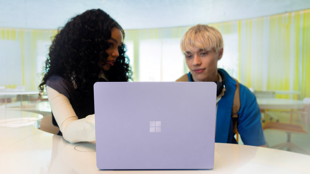 A woman and man at a table using a Surface Laptop Copilot+ PC