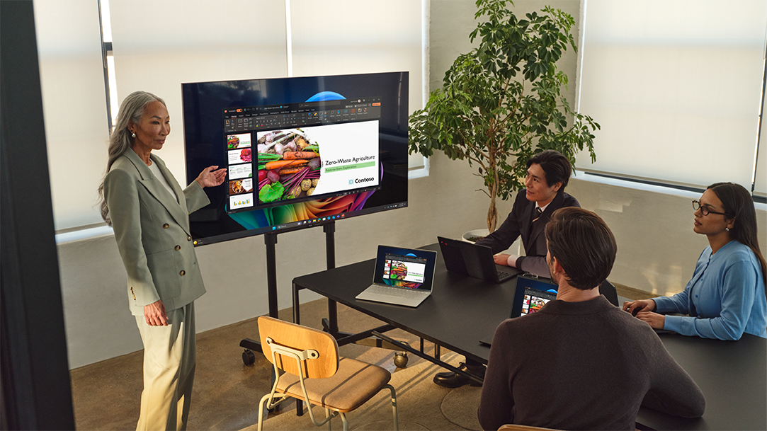 A woman connects a Windows 11 PC to a TV wirelessly and presents to a team
