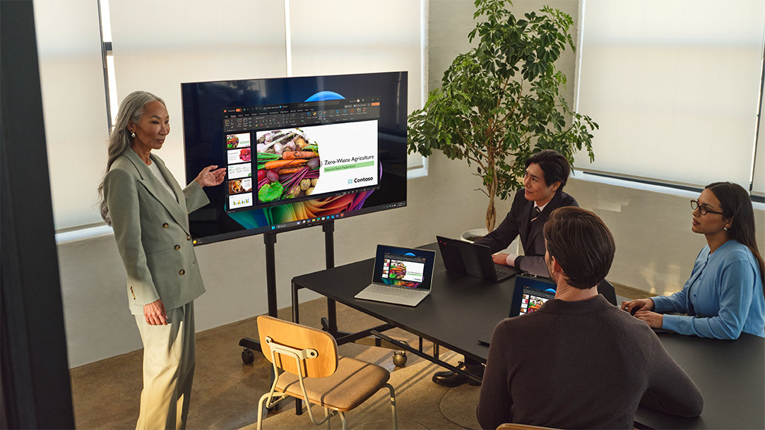 A woman connects a Windows 11 PC to a TV wirelessly and presents to a team