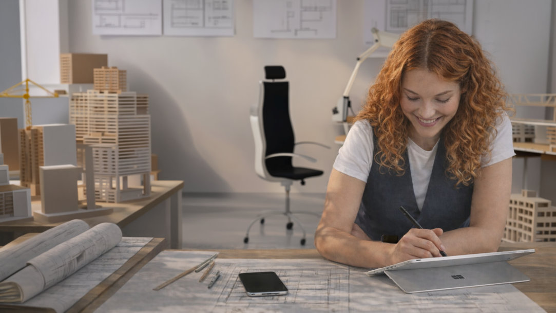A woman in an architect’s studio using a Surface Pro in tablet mode and a Surface Slim Pen 