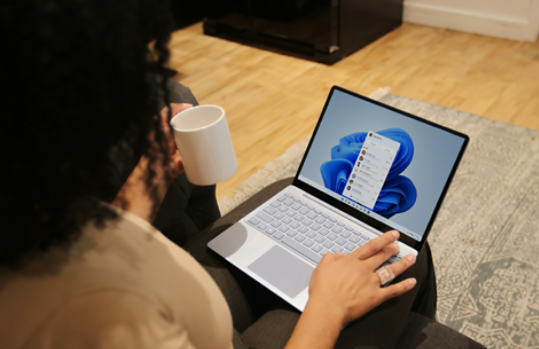 A woman on her Surface device working and drinking coffee