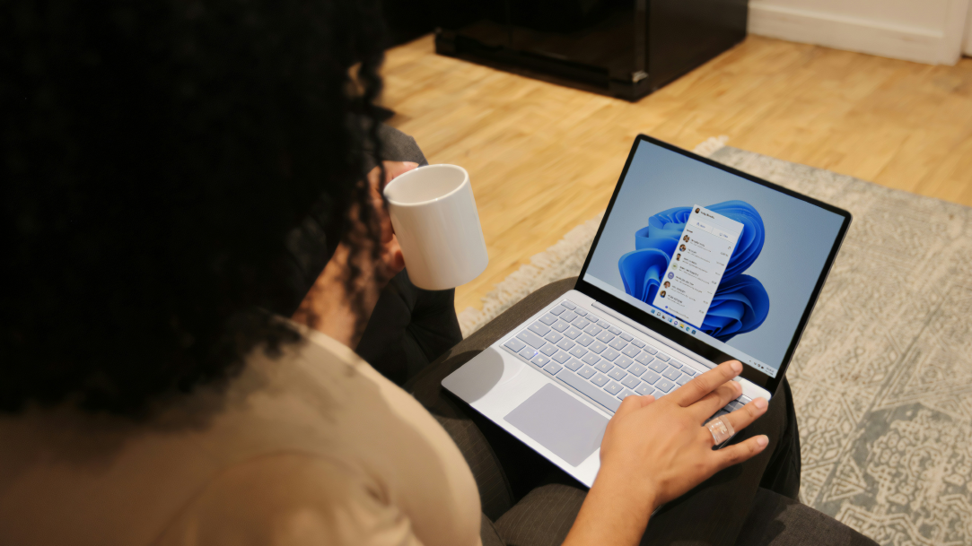 A woman on her Surface device working and drinking coffee