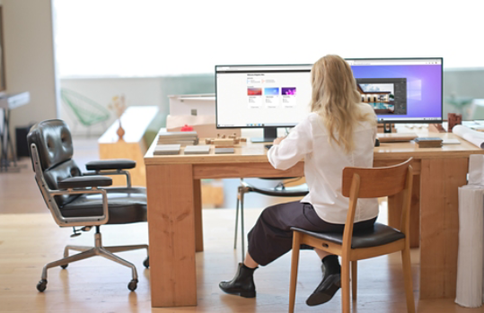 A woman sitting at a desk with multiple monitors