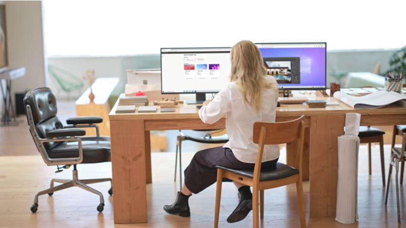 A woman sitting at a desk with multiple monitors