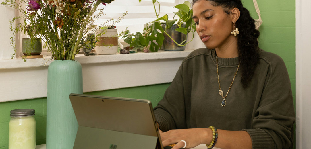 A woman sitting at a table typing on her PC