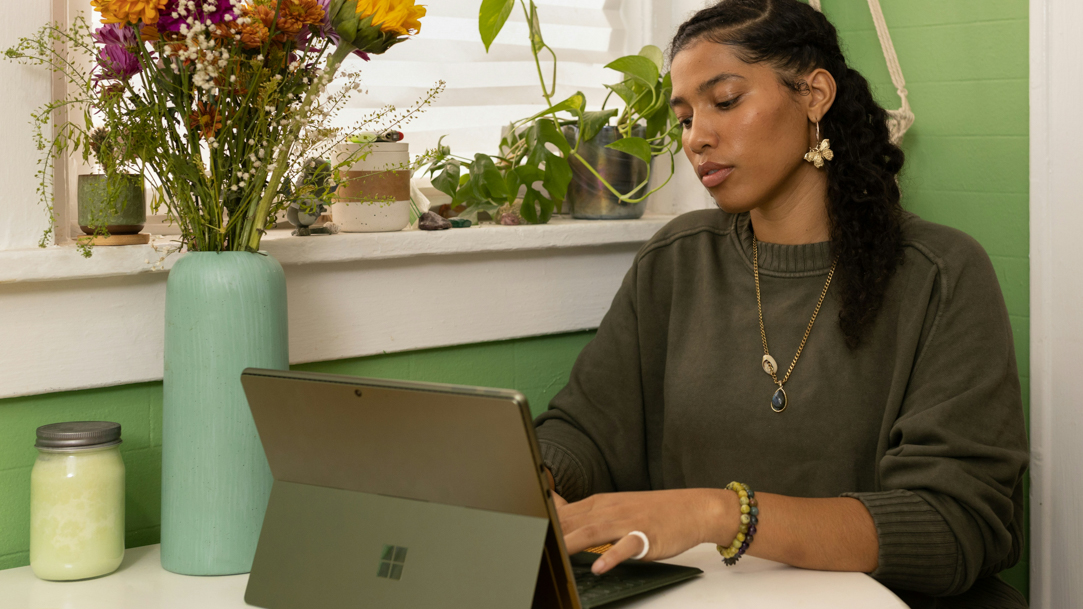 A woman sitting at a table typing on her PC