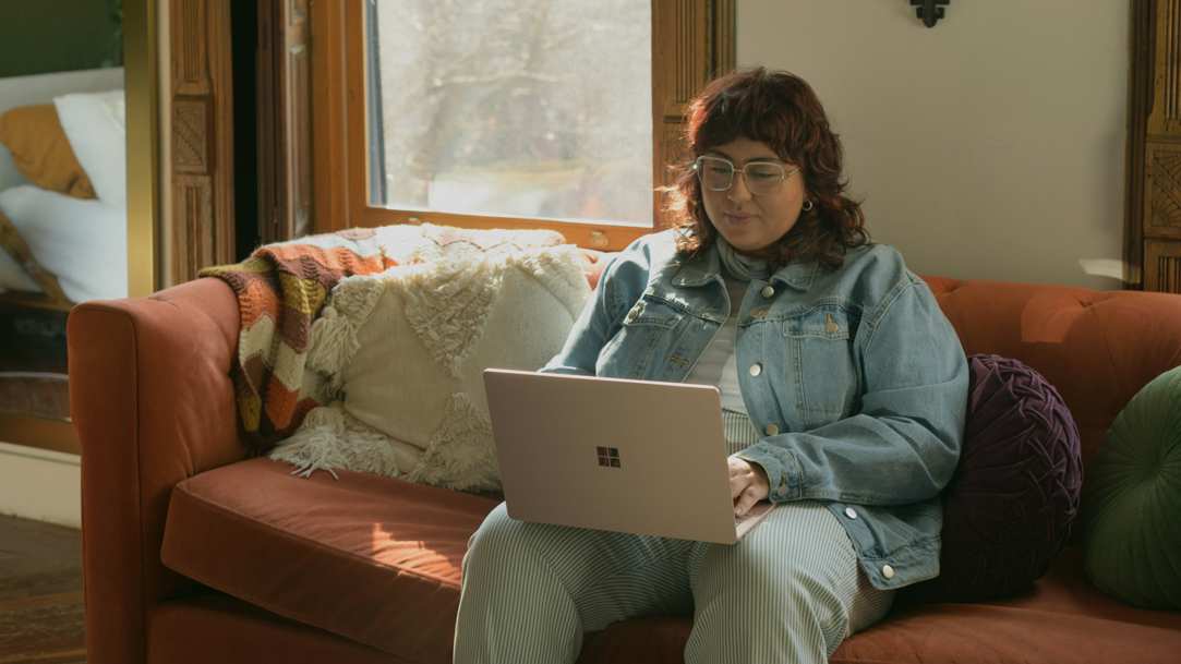 A woman sitting on a couch using a laptop