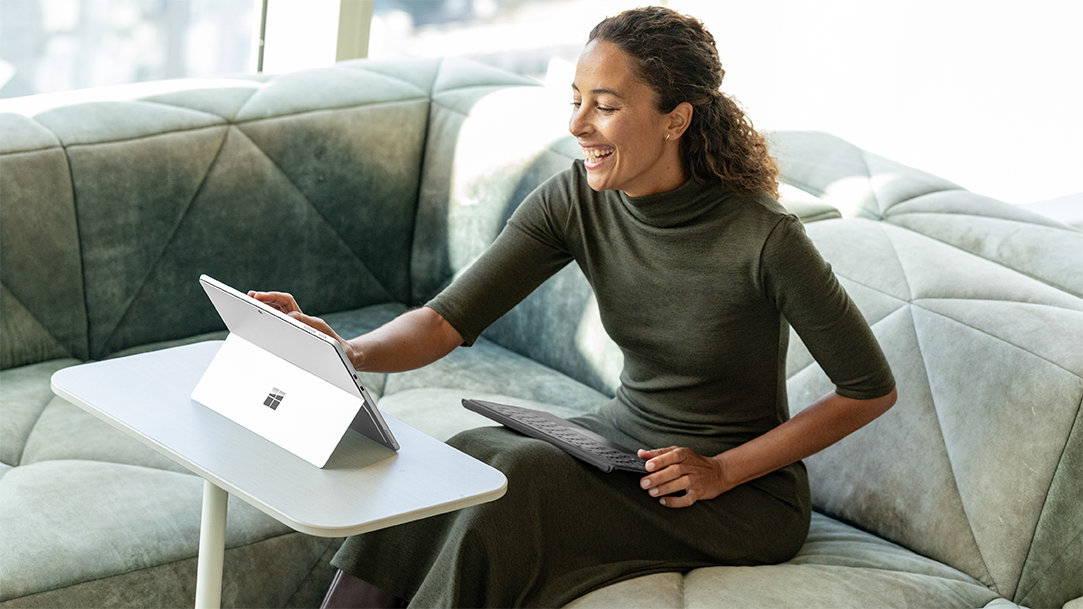 A woman sitting on a couch with a Surface Pro learning how to customize Microsoft Edge browser tab pages