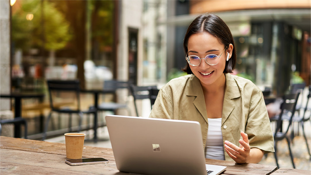 A woman sitting outside with her computer doing a voice search in Microsoft Edge