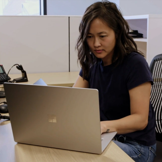 Eine Frau tippt auf ihrem Surface Laptop 5 in einer Büroumgebung