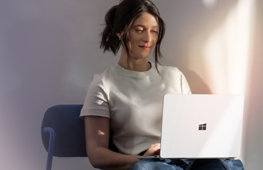 A woman using a Surface Laptop 7th Edition on her lap