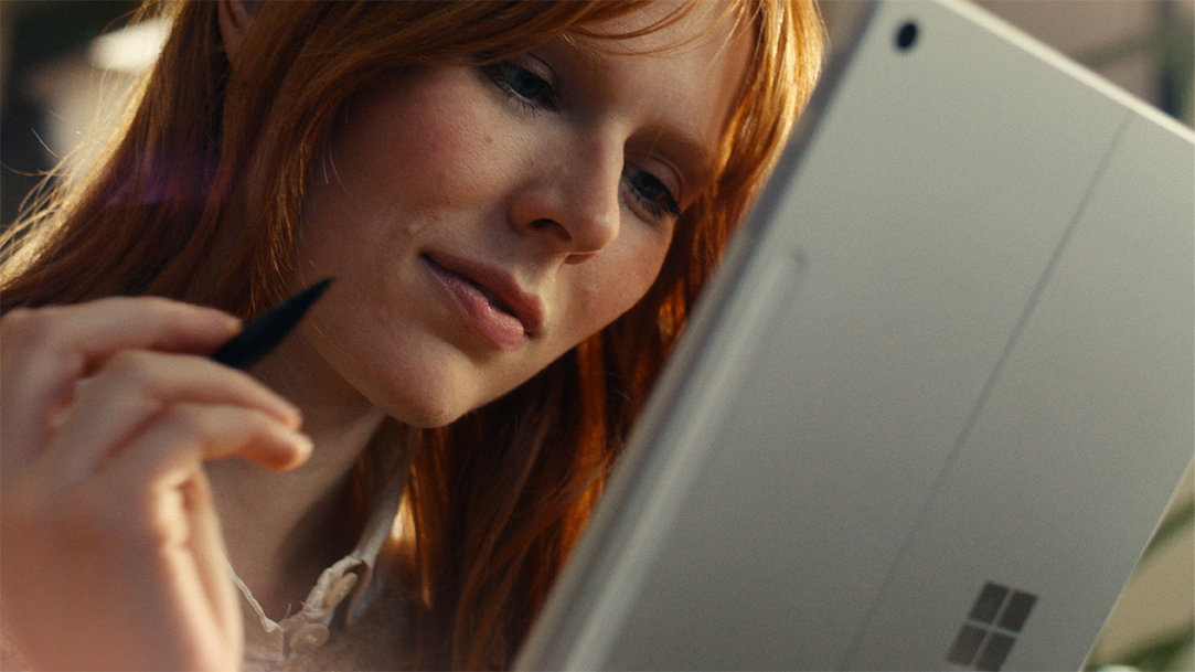 A woman with a Surface Slim Pen in her hand and using a Surface Pro in tablet mode