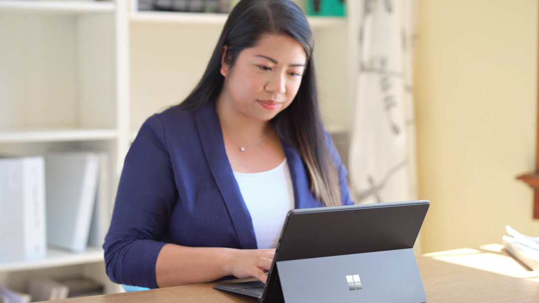 A woman working on a Microsoft Surface 2-in-1 PC