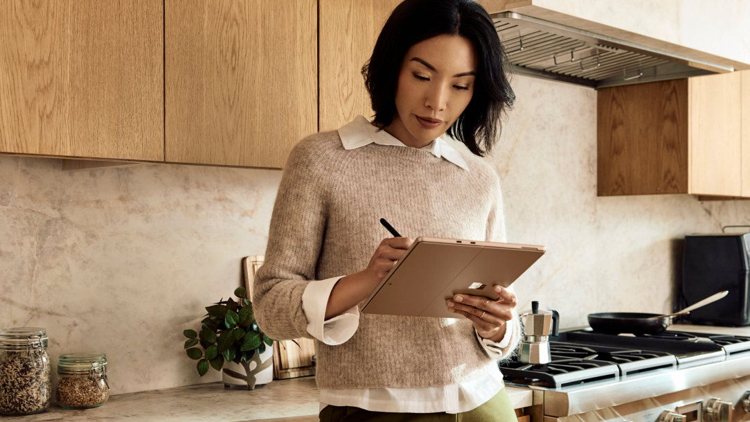 A woman writes with a Surface Slim Pen on her Surface Pro