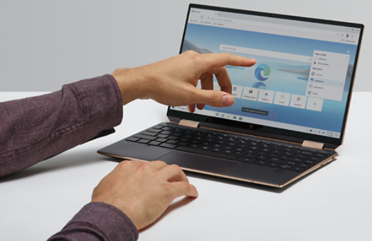 A woman’s hand pointing to a laptop with Microsoft Edge on the screen