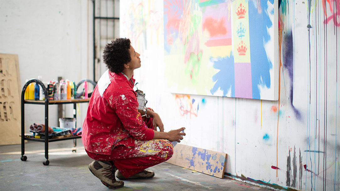 A young creative artist is working with graffiti style spray paints in his studio space