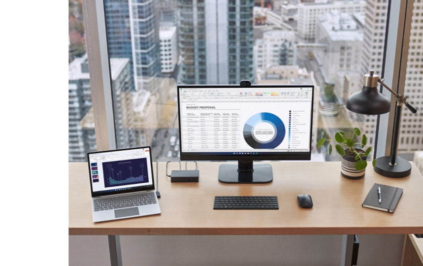 사무실 책상 위의 Surface 도킹 스테이션에 연결된 Surface 디바이스. 옆에는 외부 모니터, 키보드, 마우스, 펜, 노트북이 놓여 있습니다