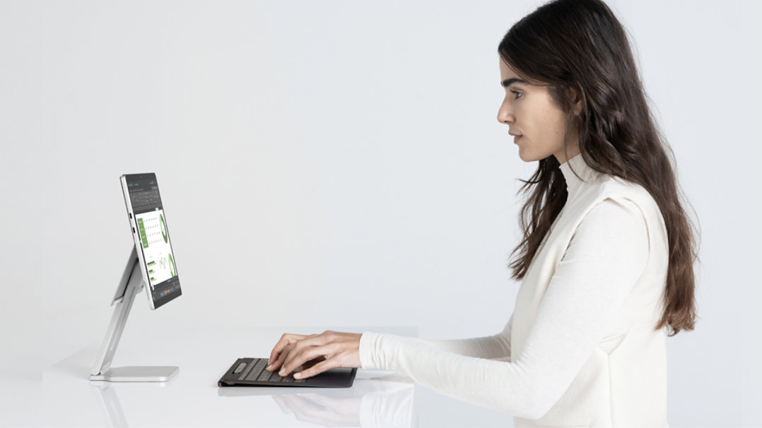 一位女士在 Surface Pro Flex 键盘前工作的图片，该键盘与处于平板模式的 Surface Pro 相分离。