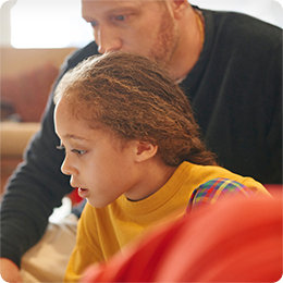 Odrasla in mlada oseba skupaj uporabljata računalnik.