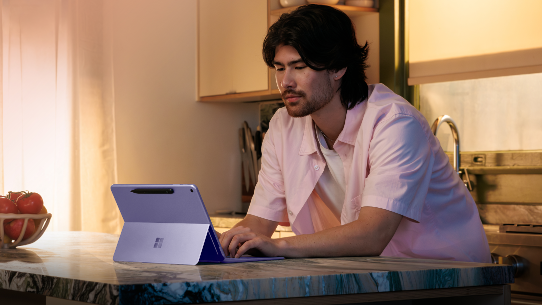 An adult male in a kitchen using a Surface Pro 2-in-1 with an attached keyboard
