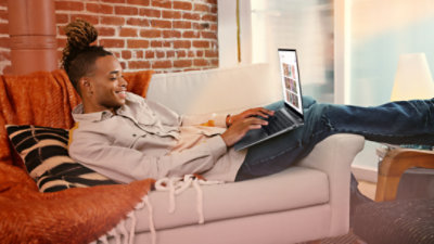 An adult male relaxing on a comfortable sofa and using keyboard shortcuts on his Windows laptop