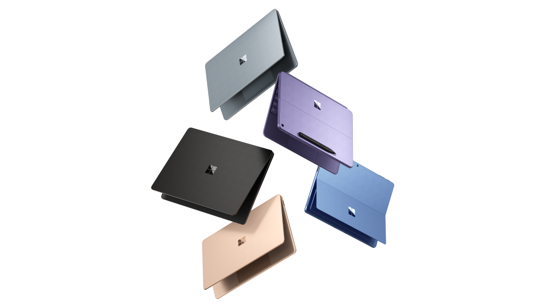 An image of three Surface Laptop Copilot+ PCs and two Surface Pro Copilot+ PCs floating in the air
