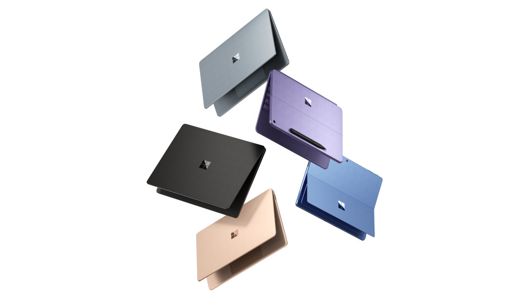 An image of three Surface Laptop Copilot+ PCs and two Surface Pro Copilot+ PCs floating in the air