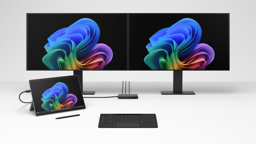 An image of a Surface Pro, Copilot+ PC with a Surface Slim Pen 2 and docked with two external monitors