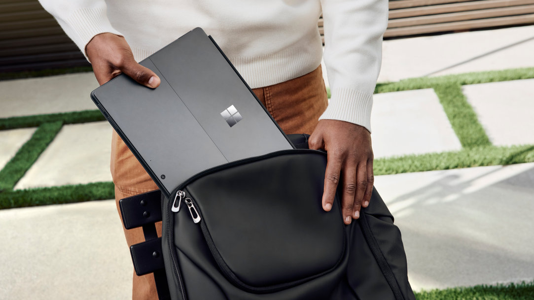 An image of a man on the go putting his Surface Pro 2-in-1 into a backpack