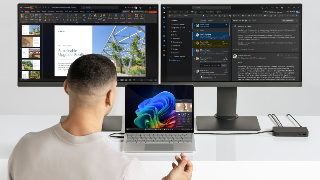 An image of a man using a Surface Laptop Copilot+ PC and dual monitors connected via a Surface dock