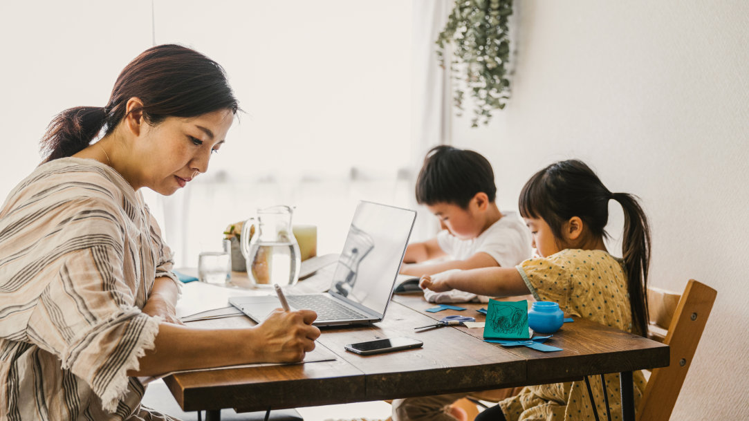 An image of a stay-at-home mom with the ability to multitask by taking care of home business on a laptop and overseeing her children’s school activities