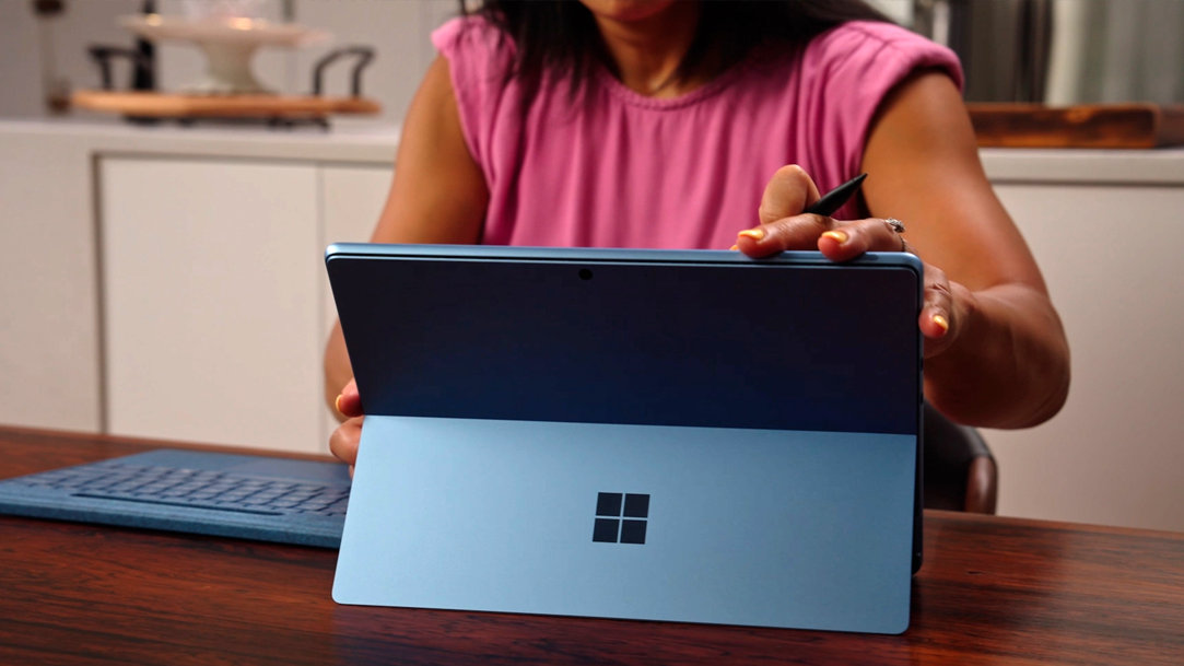 An image of a woman sitting in her kitchen with Surface Pro on a countertop