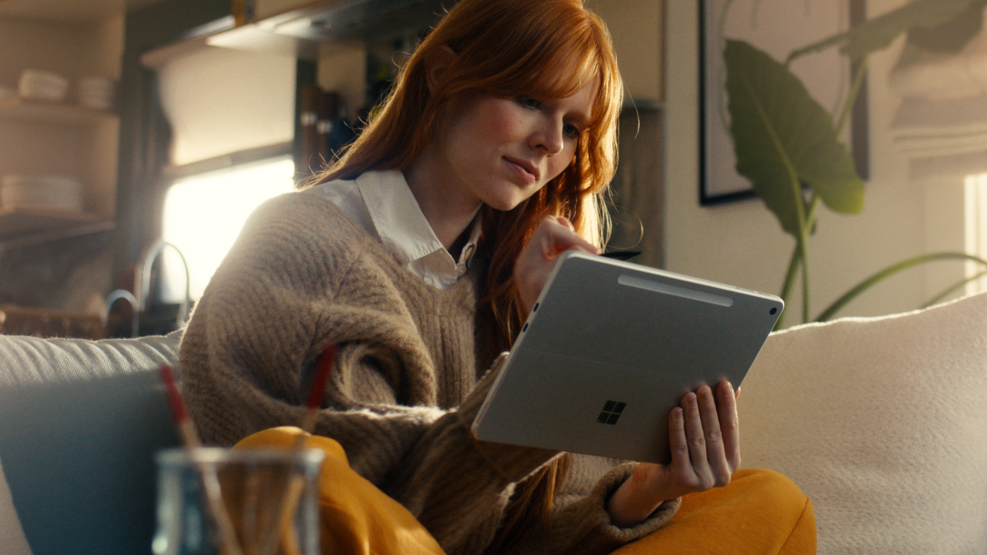 An image of a woman sitting on a sofa using a Surface Pro 12-inch