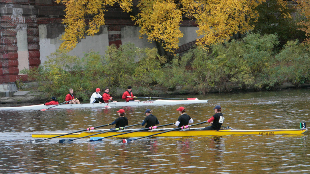 An image of collaboration in action showing two teams of competitive rowers racing on a lake