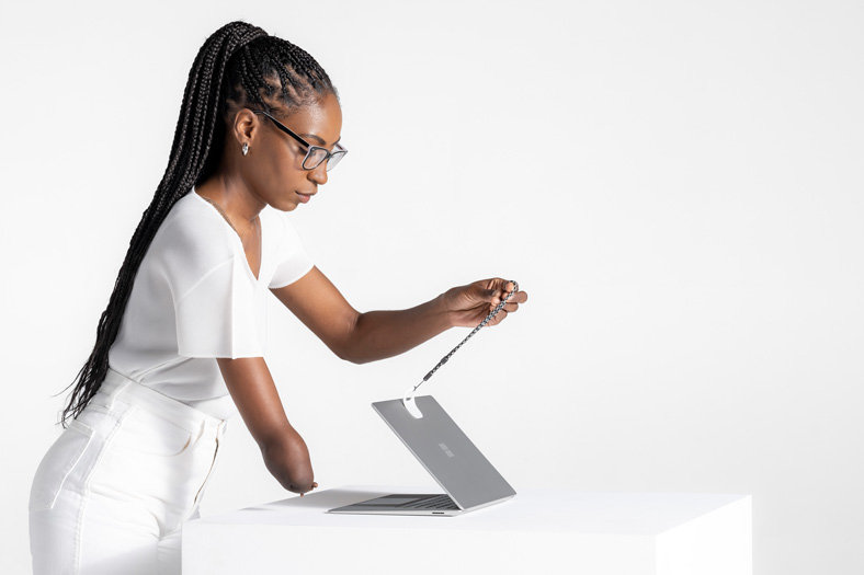 An occupational therapist works with his client to use Microsoft adaptive accessories to use a Surface Laptop 5 device.