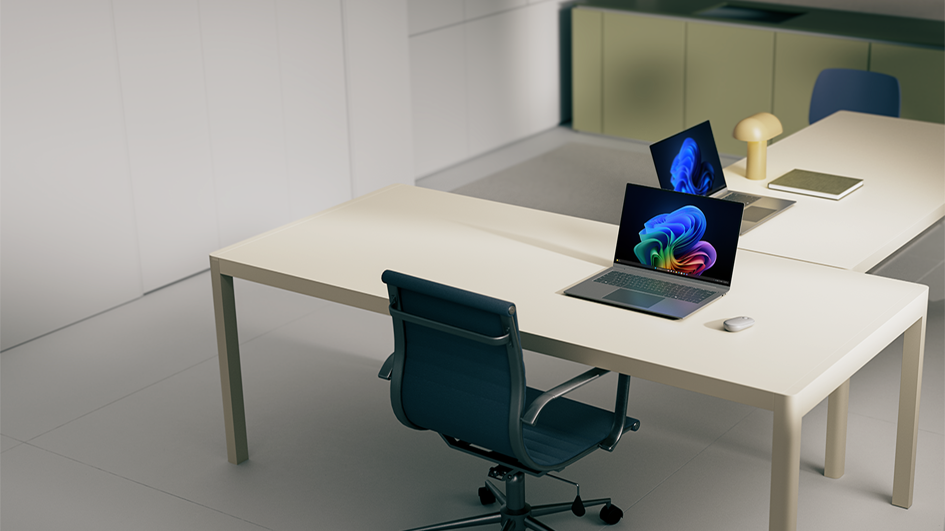 Two office workstations, with desks, both with open Windows 11 Pro PCs displaying bloom images, a mouse, a lamp, and a notebook