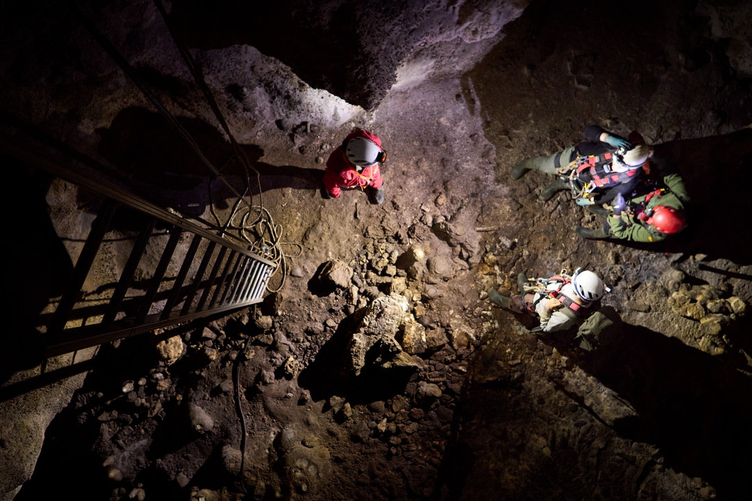 Birdseye view of archeologists inside a deep chamber of a remote Spanish cave