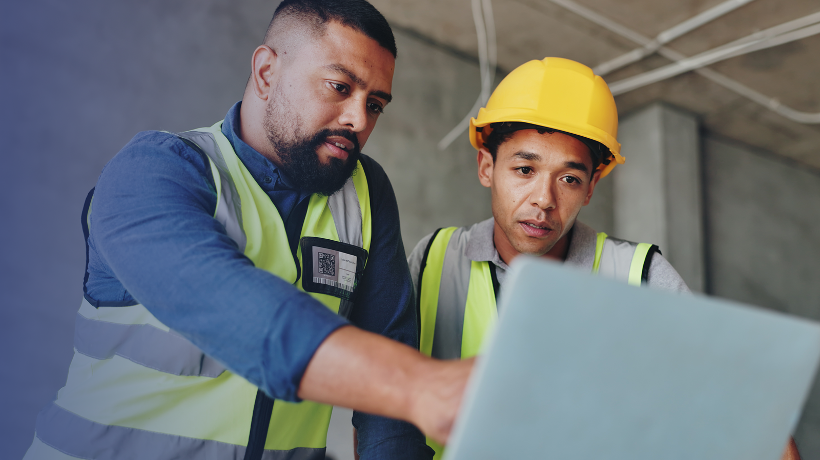Two construction workers on a job site looking at a Windows Pro laptop