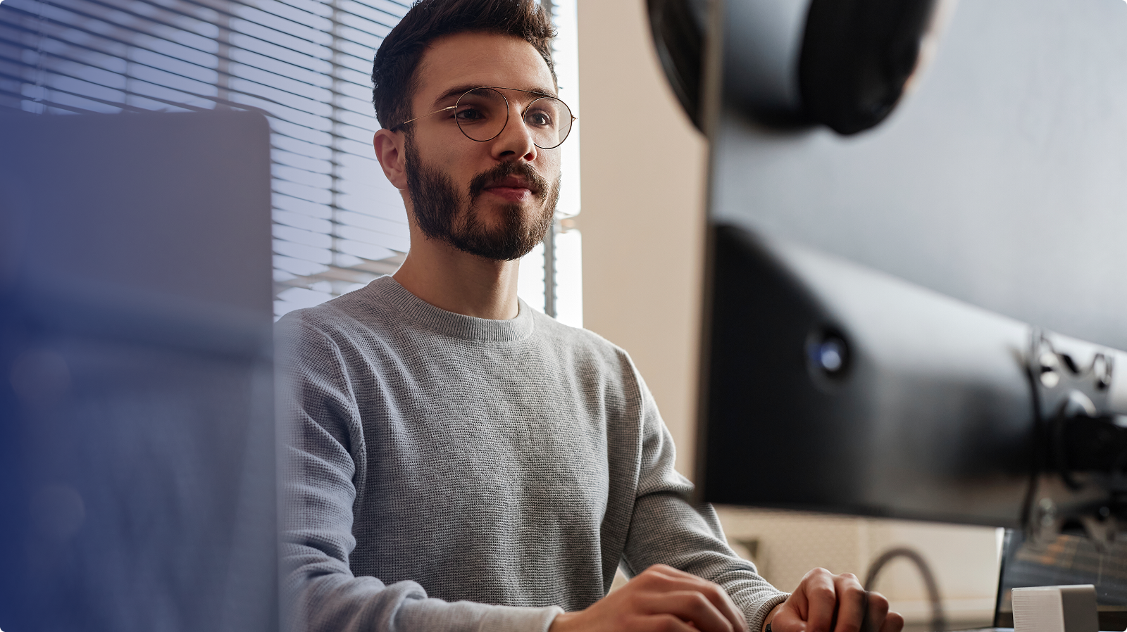An office worker sitting at a workstation looking at a large external computer screen