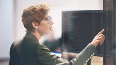 Frauen im Kostüm zeigen auf Daten, die auf einem Bildschirm angezeigt werden