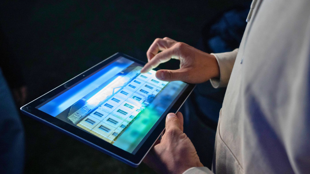 Close-up of a Surface Pro device displaying the facade of a French chateau as a person moves his hand along the screen