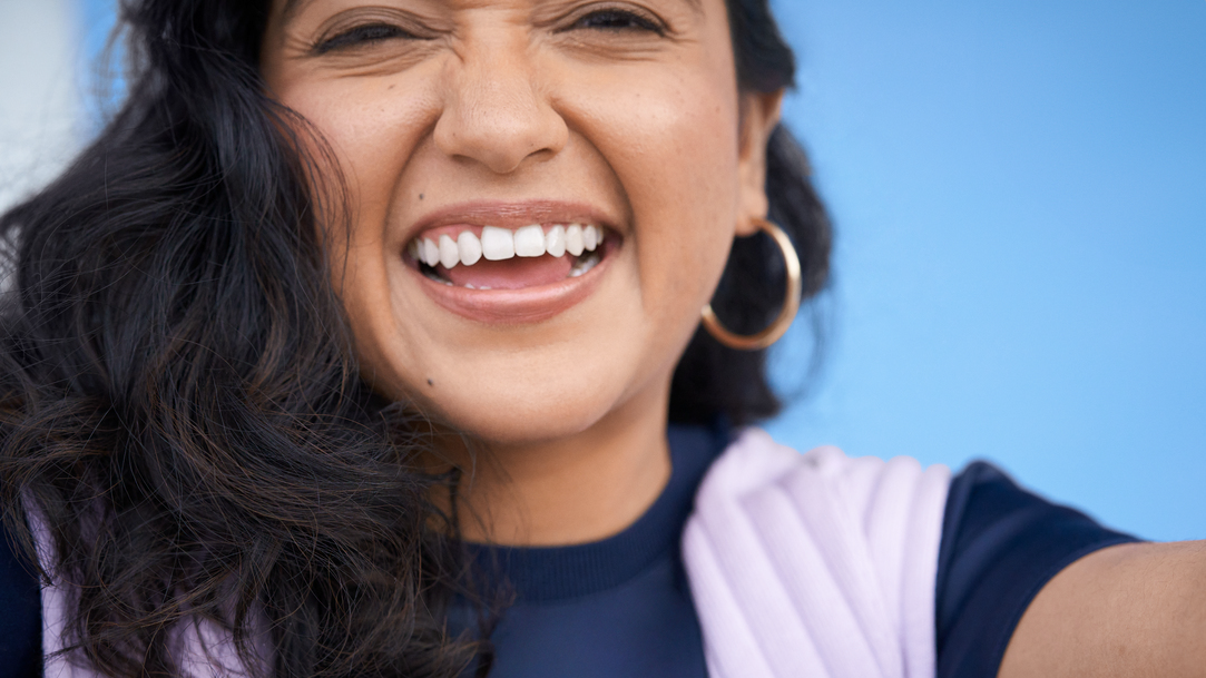 Close-up portrait of a woman smiling with a light blue background