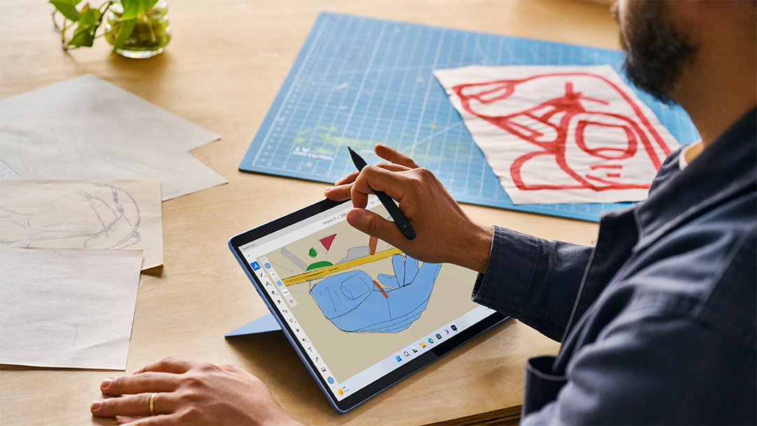 Contextual image of male artist inside working on Surface Pro 9 Sapphire