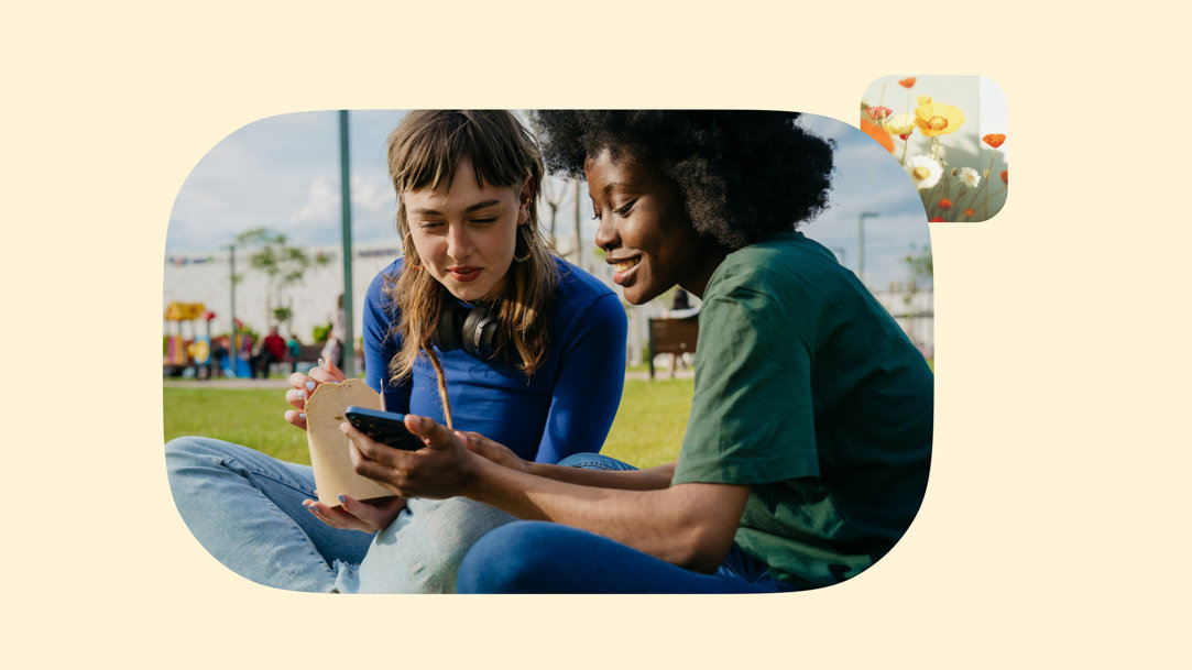 Two people sitting outside looking at a phone