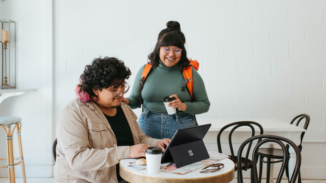 Couple sitting at a table in a café, looking at their computer