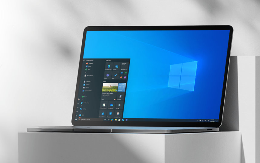 Laptop on a white pillar open to Windows 10 home screen.
